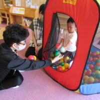 幼児とボールを受け渡す中学生